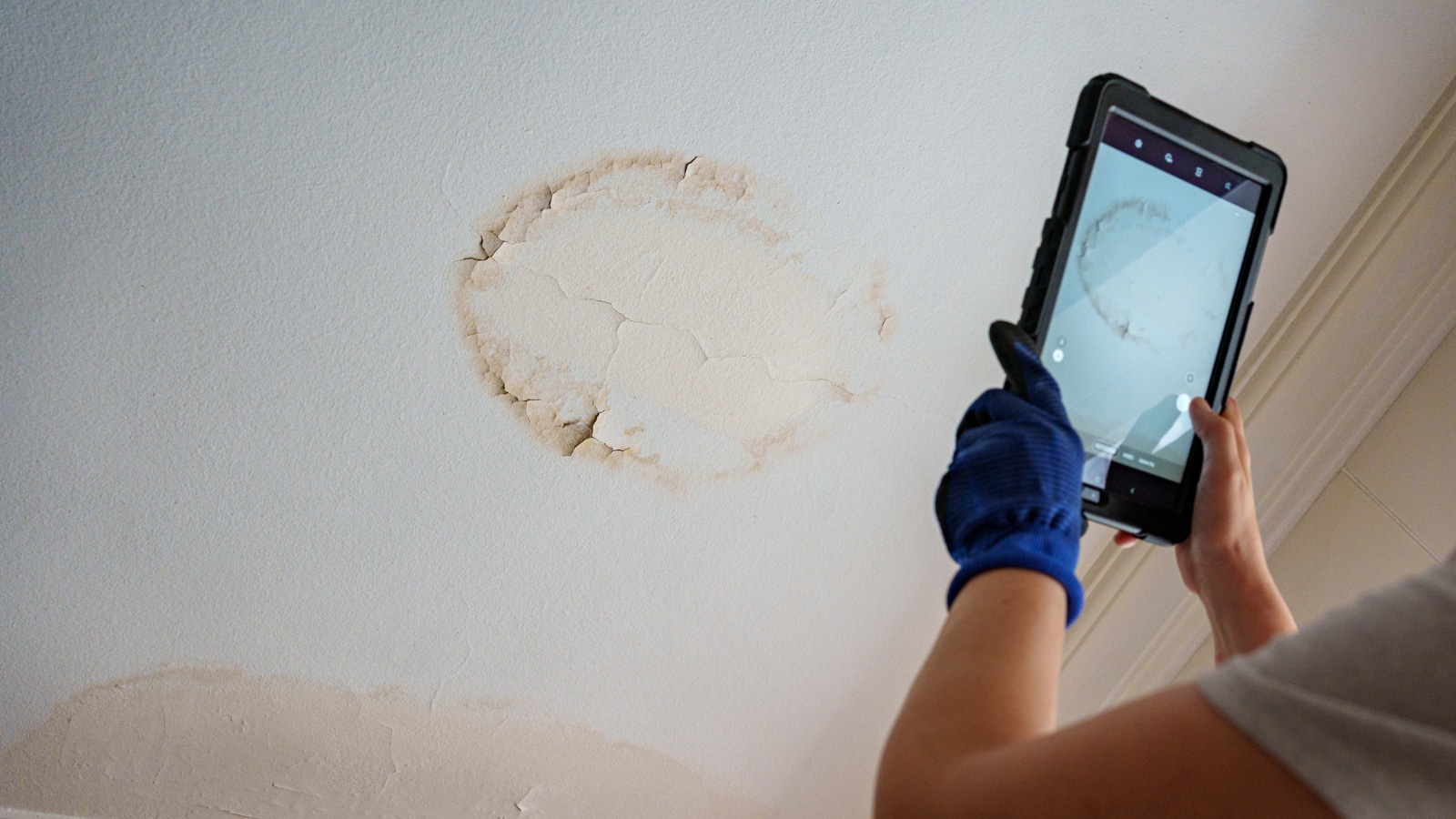 worker taking photo on ipad of water damage